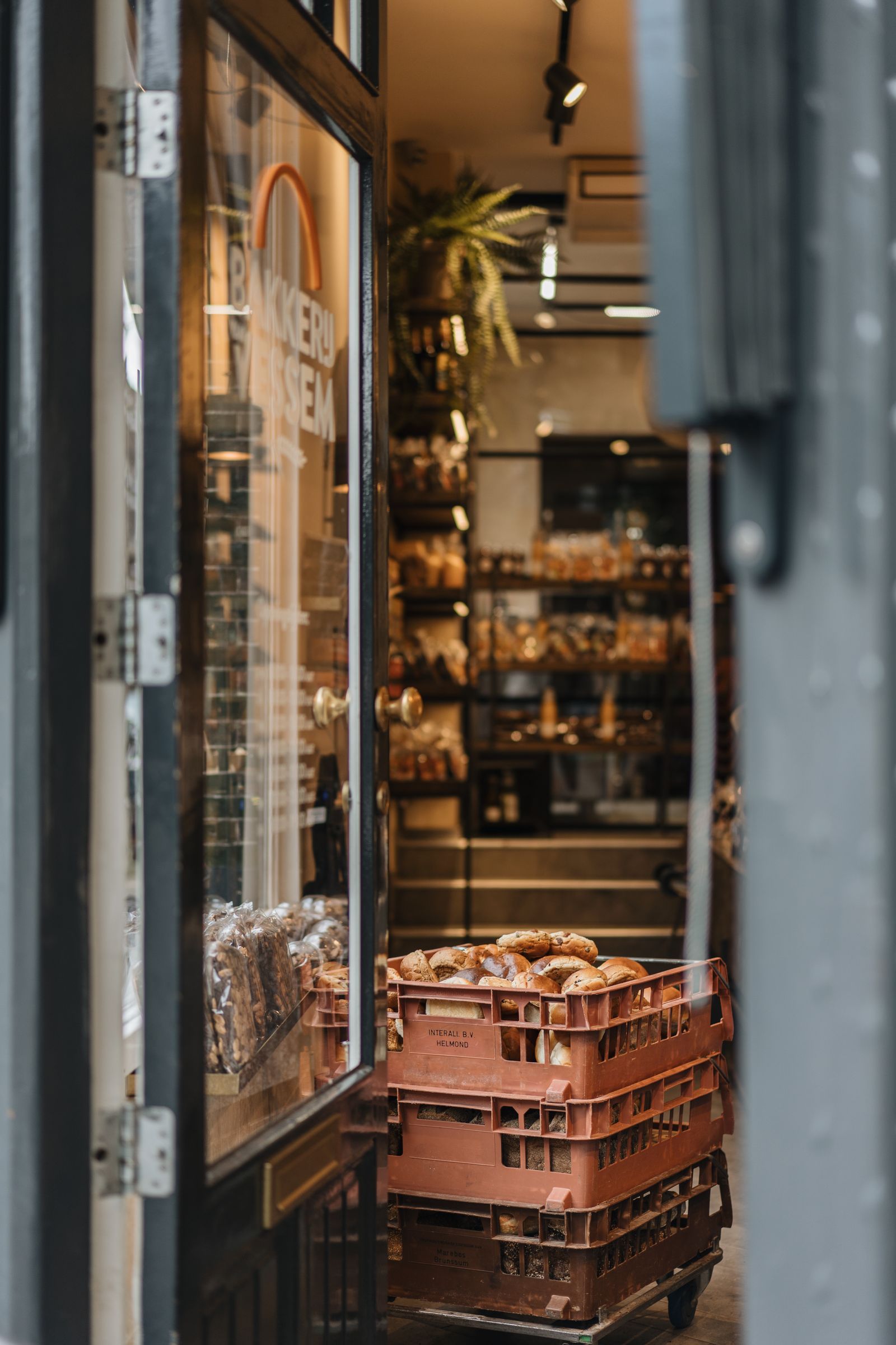 Stacked crates of fresh bread outside a bakery storefront, ready for delivery