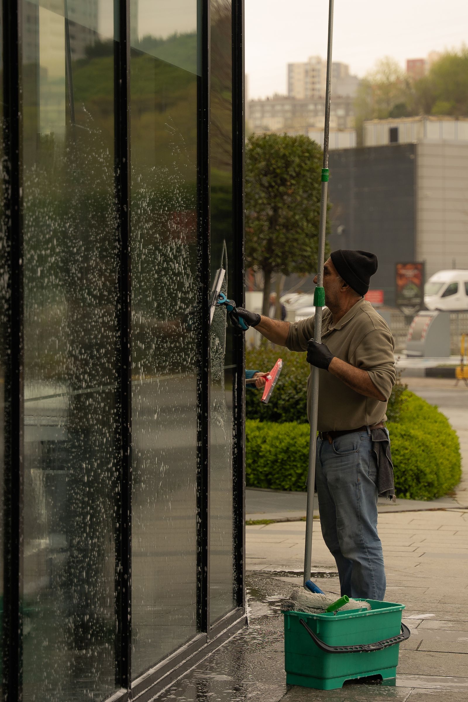 A professional window cleaner using a squeegee on a glass building facade